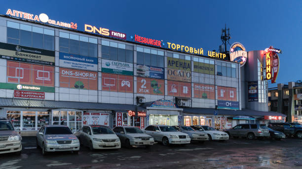 Night view of facade building of shopping center and cars parked in parking lot in front of store stock photo
