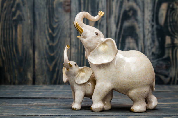 Cute Baby and Mother Elephant Figurines on Blue Background Cute baby and mother elephant figurines on blue wooden background elephant figurine stock pictures, royalty-free photos & images