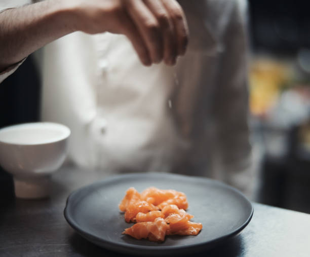 istock Restaurant Chef cook preparing salmon filet and salting it. 952322350