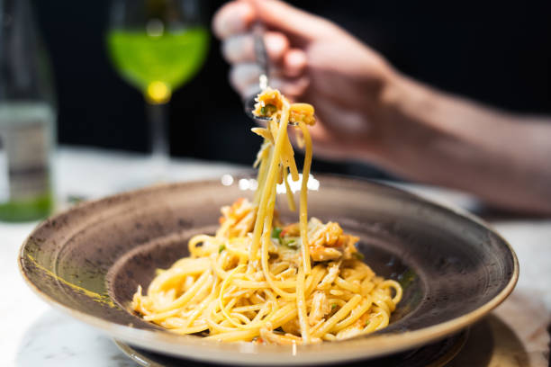 istock Young woman is holding fork with seafood pasta. 952323644