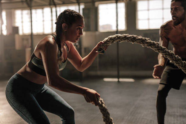 young woman working out with battle ropes - crosstraining imagens e fotografias de stock