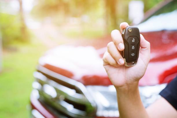 istock lady female holding car keys with car on background. 952331690
