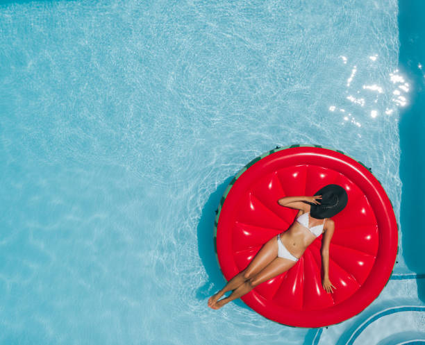 istock Woman sunbathing on floating mattress in swimming pool 952337452