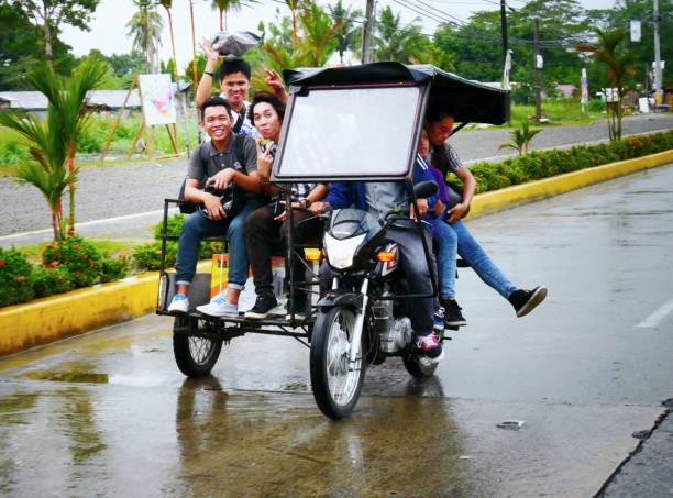 motorcycle with a sidecar TAGUM CITY, PHILIPPINES—MARCH 2016: Passengers riding a motorcycle with a sidecar pose for the camera while driving along a wet street in Tagum City. philippines tricycle stock pictures, royalty-free photos & images