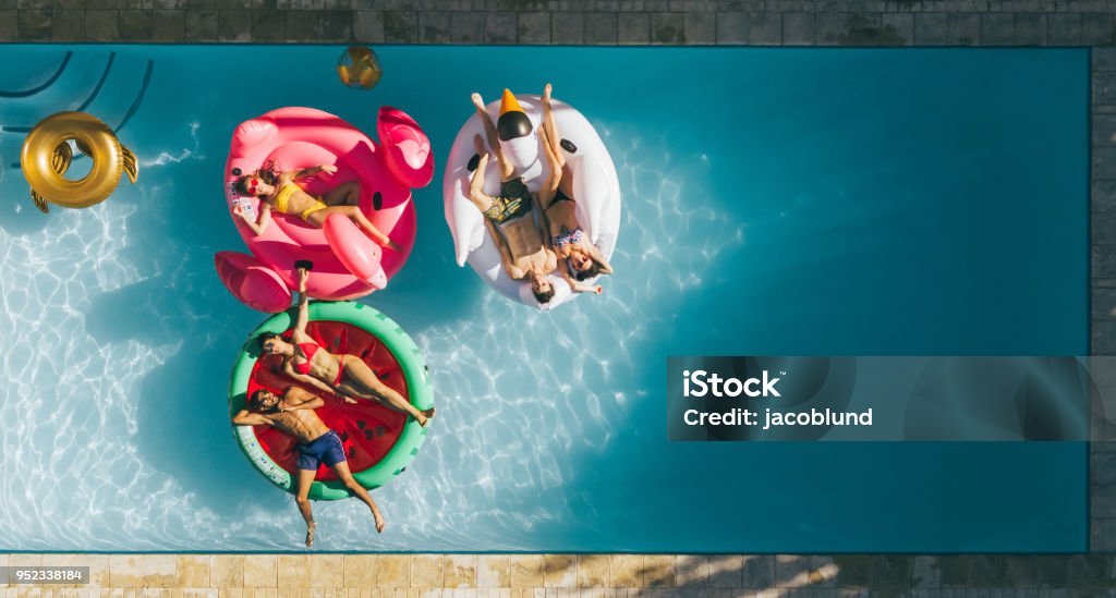 Amis, reposantes sur des matelas gonflables dans piscine - Photo de Piscine libre de droits