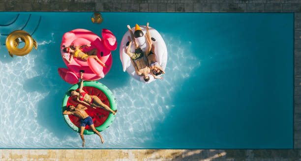amis, reposantes sur des matelas gonflables dans piscine - floating on water swimming pool men water photos et images de collection