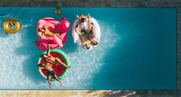 istock Friends relaxing on inflatable mattresses in pool 952338184