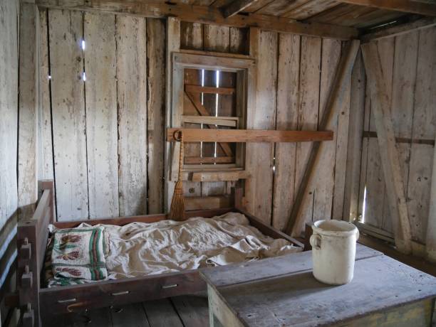 Slaves’ bedroom Wooden bed with table and a pail inside a slave’s quarters in an old plantation house in Louisiana slave quarters stock pictures, royalty-free photos & images