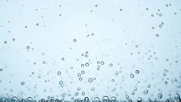 Small bubbles of oxygen on blurred blue background. At the bottom of the larger. In the upper part of the image smaller bubbles.