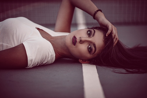 Beautiful Smiling Girl Lying Down on Tennis Court and Posing