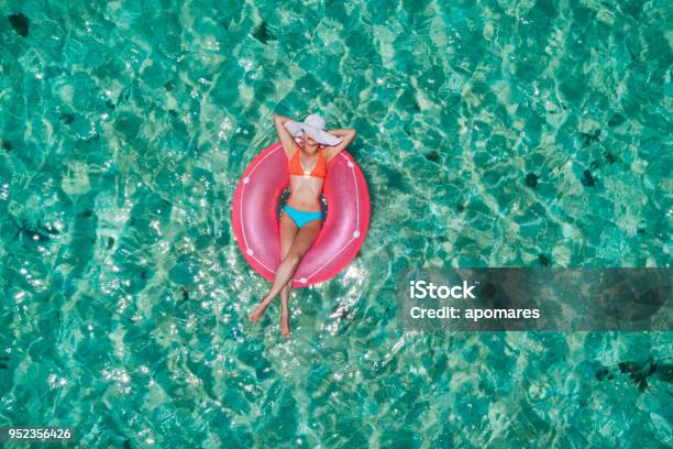 Aerial View Of A Young Women Relaxing On Inflatable Ring In A Tropical Turquoise Pristine Beach Stock Photo - Download Image Now