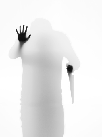 Man holding a knife behind the frosted glass