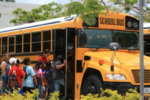 students boarding a school bus in Saipan SAIPAN, CNMI—Students and their chaperones board a school bus at a field trip in Saipan, Northern Mariana Islands in April 2015. field trip stock pictures, royalty-free photos & images