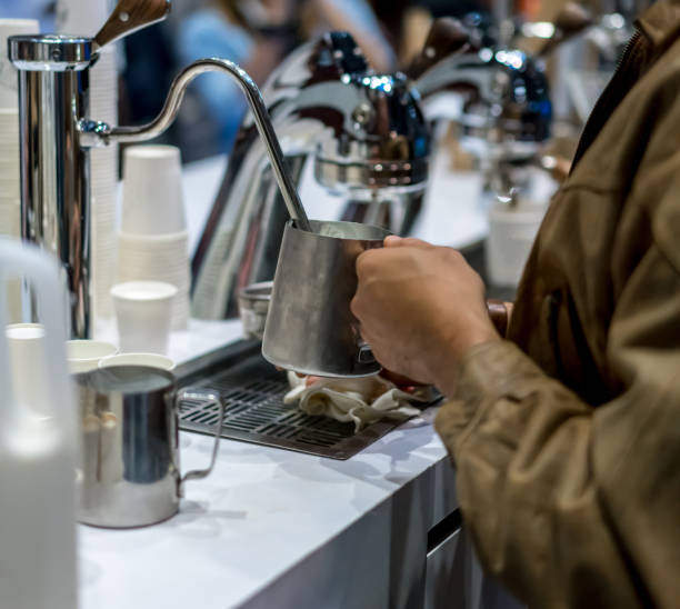 istock Barista Cafe steaming milk in stainless container. Coffee Preparation Service Concept 952361902