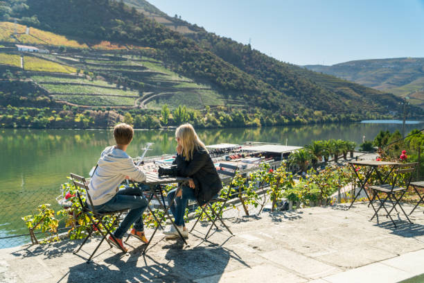 due giovani donne si rilassano osservando una splendida vista su una riva del fiume douro a pinhao, in portogallo - the douro foto e immagini stock