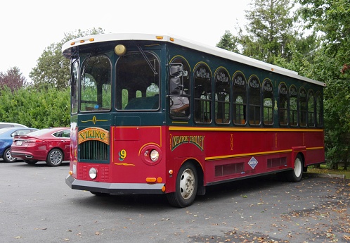 NEWPORT, RHODE ISLAND—SEPTEMBER 2017:  A red and green Viking trolley bus waits for tourists outside an old mansion during a tour at the Bellevue Avenue.