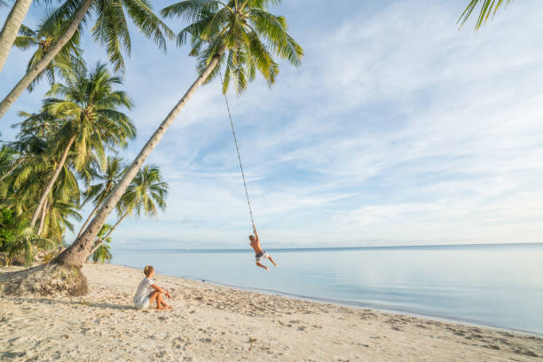 pareja jugando en la playa, cuerdas del columpio en el árbol de palma en asia tropical de la isla - columpio de cuerda fotografías e imágenes de stock