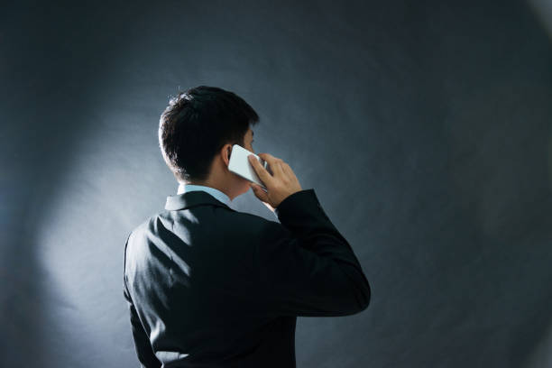 Rear view of businessman using phone on black background