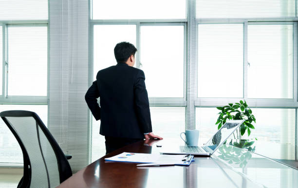istock Businessman looking out window in office 952375414