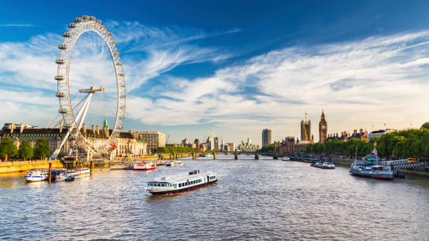 Westminster Parliament, Big Ben and the Thames with blue sky LONDON, JULY 2017 - View of Westminster Parliament, Big Ben and London Eye with Thames and tourist ship in foreground on a sunny summer afternoon thames river stock pictures, royalty-free photos & images