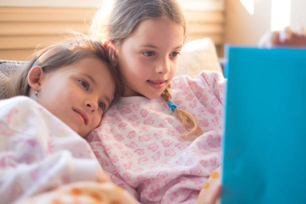 istock Cute sisters reding a book in the morning 952379840