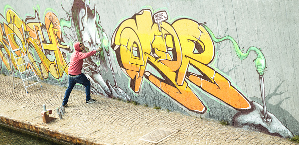 Colorful graffiti on wall at skate park. Closeup street art drawing with aerosol color spray at skatepark. Pattern of different colors on wall. Urban subculture self expression modern art concept.