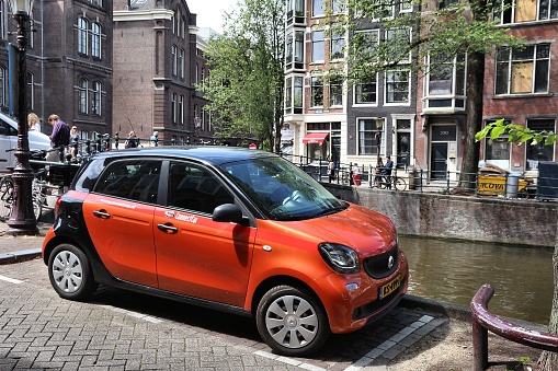 ConnectCar car sharing vehicle Smart parked by the canal in Amsterdam. Netherlands has 528 registered cars per 1,000 inhabitants.