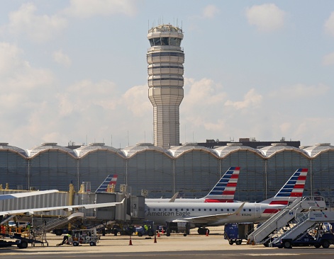 ARLINGTON COUNTY, VIRGINIA—SEPTEMBER 2017: An American Eagle aircraft loads passengers and cargo with the control tower of Ronald Reagan Washington National Airport in the background.