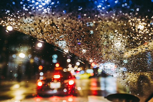 Raindrops on the windscreen with defocused traffic in the rain