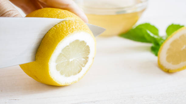 istock Macro image of cutting fresh lemon on white wooden board 952388764