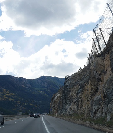 COLORADO, USA—OCTOBER 2017:  Winding roads with wire netting placed on the cliff wall to stop rocks from falling into the highway  along Interstate 70 in the Colorado Rockies.