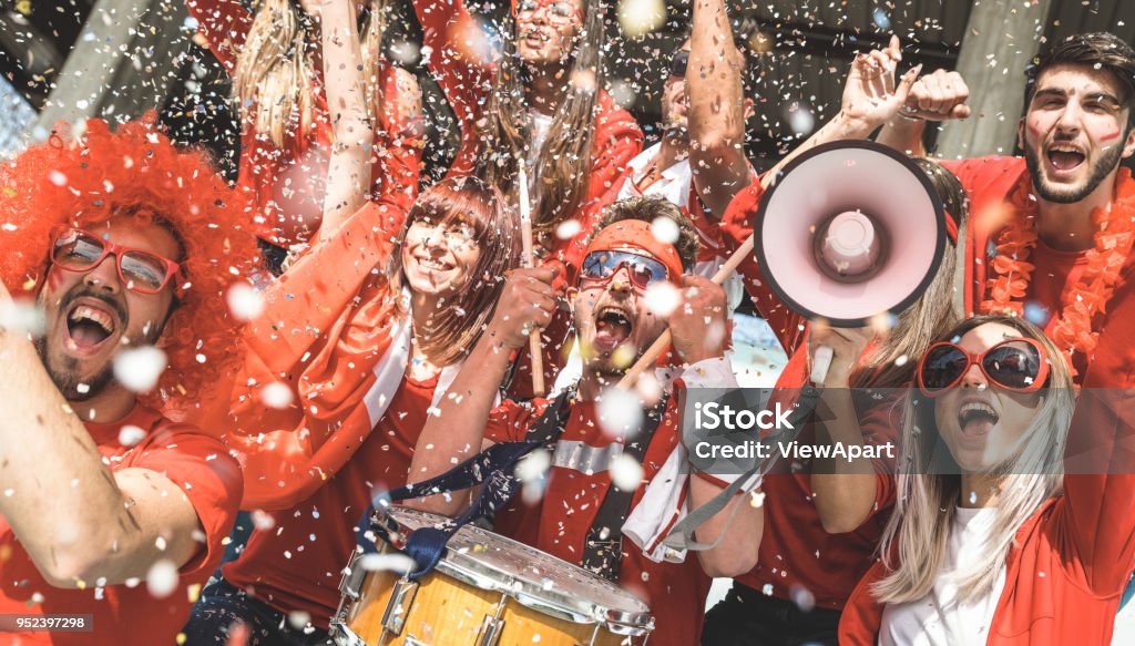 Amici tifosi tifosi di calcio che tifano con coriandoli guardando l'evento delle partite di calcio allo stadio - Gruppo giovani con magliette rosse che si divertono eccitati sul concetto di campionato del mondo sportivo - Foto stock royalty-free di Fan