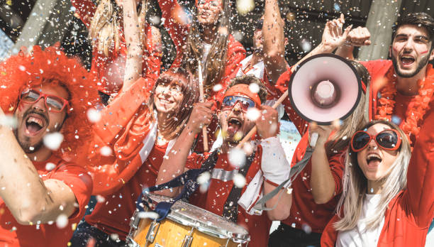 amici tifosi tifosi di calcio che tifano con coriandoli guardando l'evento delle partite di calcio allo stadio - gruppo giovani con magliette rosse che si divertono eccitati sul concetto di campionato del mondo sportivo - fan foto e immagini stock