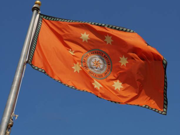 Cherokee Indian nation flag Flag of the Cherokee Indian nation of Oklahoma waving unfurled with blue skies in the background trail of tears stock pictures, royalty-free photos & images
