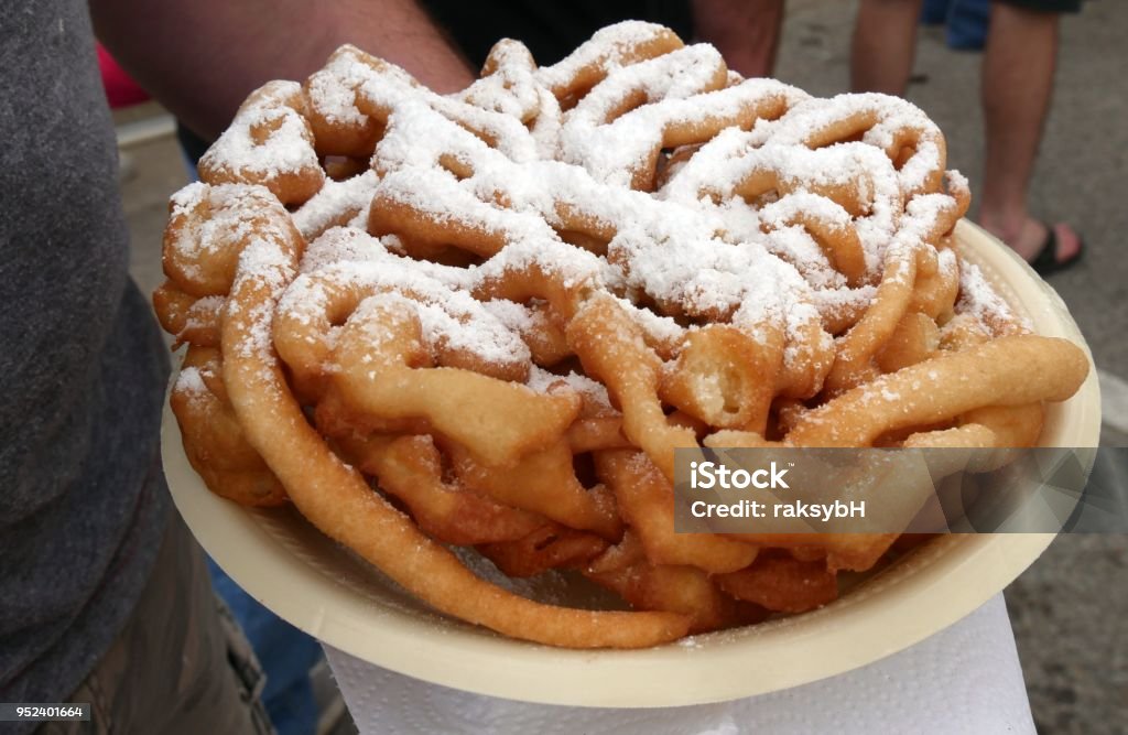 plate of funnel cake with powdered sugar A hand holding a plate of funnel cake with powdered sugar on top Funnel Stock Photo