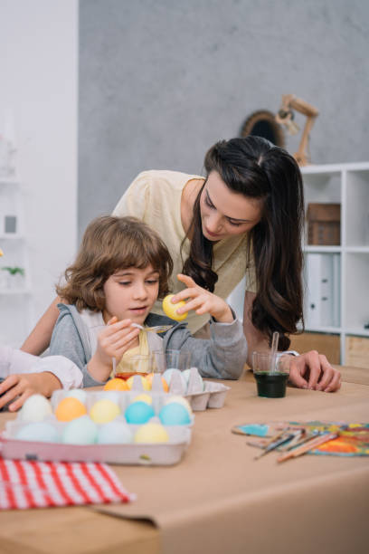 istock little son helping mother with eggs painting for easter holiday 952406534