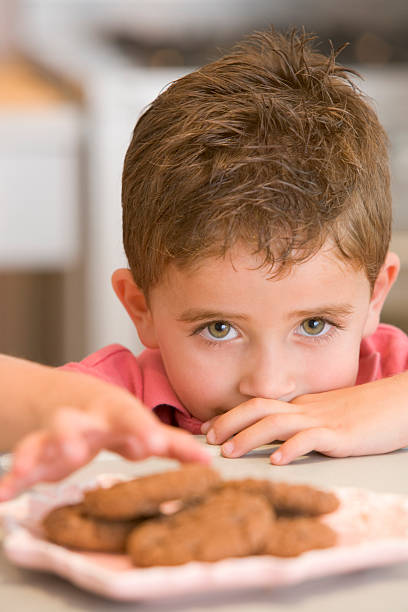 istock Young boy in kitchen eating cookies 95240780