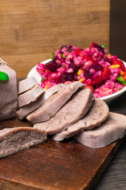 istock Boiled beef or pork tongue with beet- mushrooms -champignon salad, basil leaf, studio shot, isolated on wood background. Top view 952413824