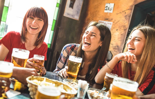 groupe de femmes copines heureux boire de la bière à la brasserie, restaurant bar - concept d’amitié avec jeunes femmes amis profiter de temps et de s’amuser véritable pub vintage cool - focus sur la fille de gauche - sélection sportive photos et images de collection