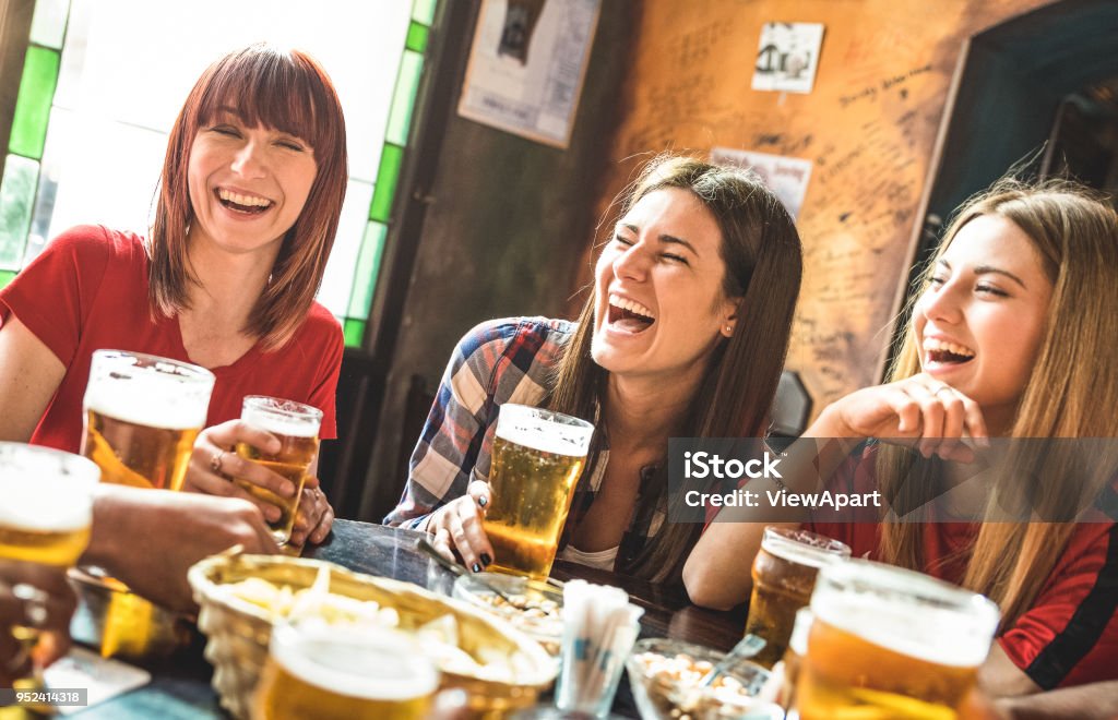 Happy girlfriends women group drinking beer at brewery bar restaurant - Friendship concept with young female friends enjoying time and having genuine fun at cool vintage pub - Focus on left girl Beer - Alcohol Stock Photo