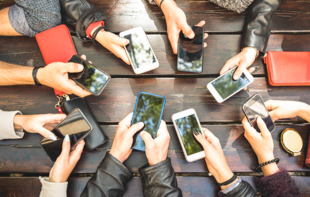 люди группы, имеющие зависимым весело вместе с помощью смартфонов - подробная информация руки обмена контентом в социальной сети с мобильн� - wireless technology фотографии стоковые фото и изображения