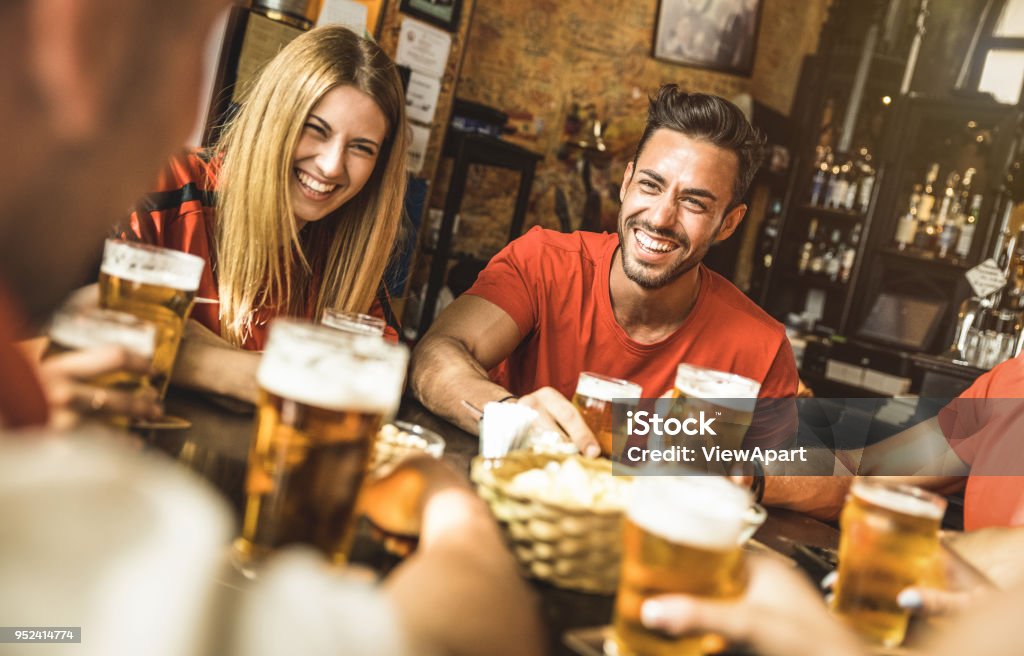 Happy friends group drinking beer at brewery bar restaurant - Friendship concept with young people enjoying time together and having genuine fun at cool vintage pub - Focus on guy - High iso image Friendship Stock Photo