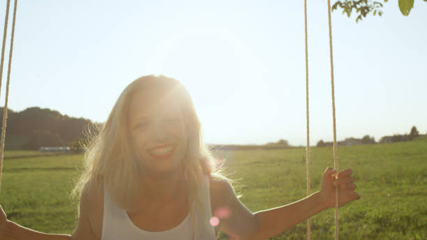 istock LENS, FLARE PORTRAIT: Joyful woman swinging in sunny nature on spring evening. 952437250