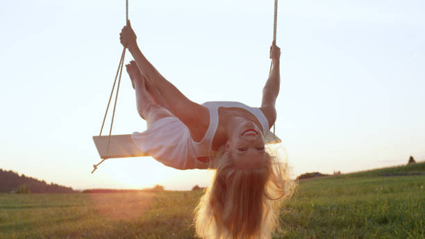 istock LENS FLARE, CLOSE UP: Attractive young woman leans back on swing while swaying. 952437436