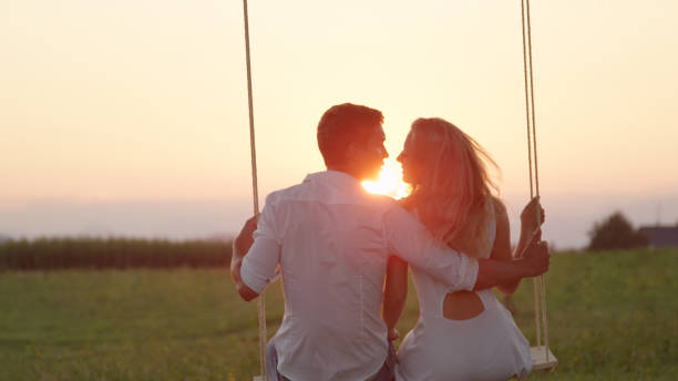 istock LENS FLARE CLOSE UP: Swaying young couple kissing in summer sunset under a tree 952437550