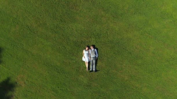 istock AERIAL TOP DOWN: Young loving parents to be lying down on grass on sunlit day 952437884