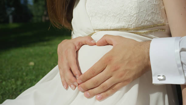 istock CLOSEUP Unrecognizable couple making heart shape with hands over pregnant belly 952452128