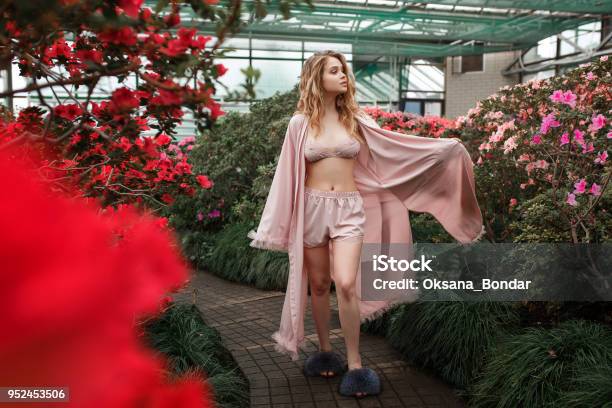 Beautiful Girl Wearing Pink Bathrobe And Lingerie Standing In Flower Garden Horizontal Full Lenght Portrait Stock Photo - Download Image Now