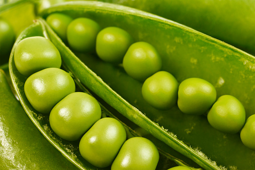 Close up of green  peas on a table with white background