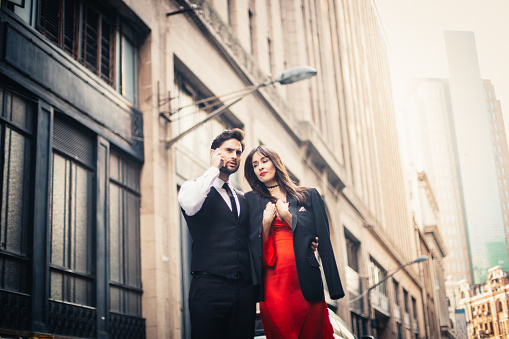 Young couple standing on the city street. Man using phone